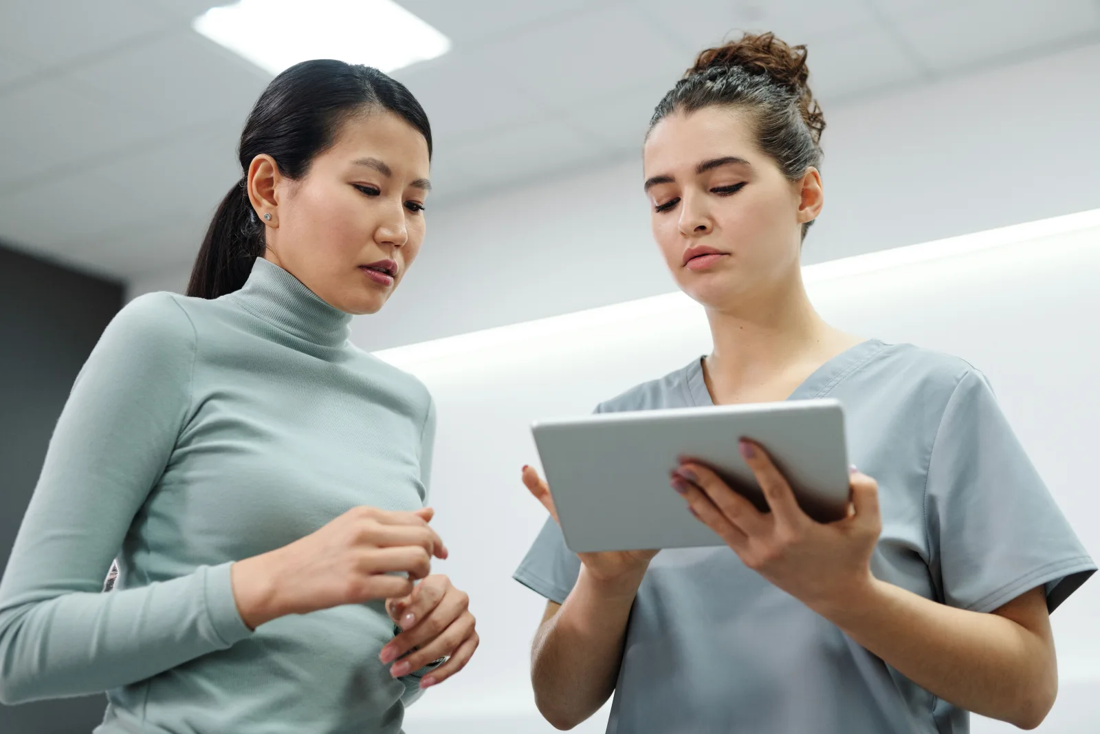 A stock consultation photograph of two women reviewing information on a tablet.